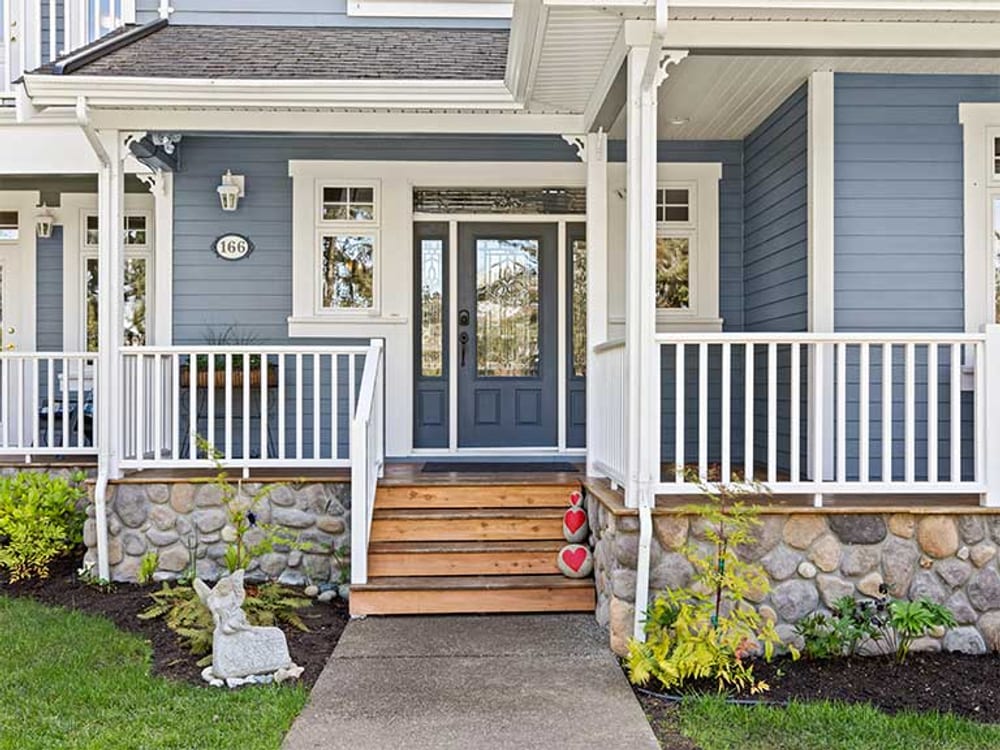 The covered front porch and steps, with planting either side of the path.