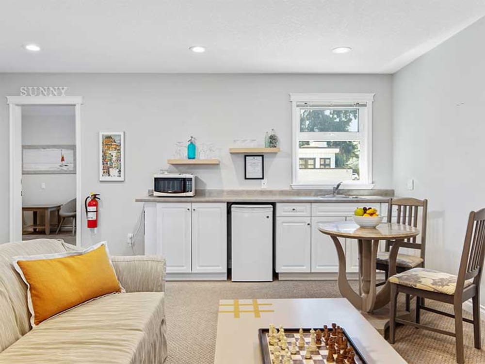 The lounge kitchenette with a microwave and counter, a sofa alongside, and a chess board set up on the low table.