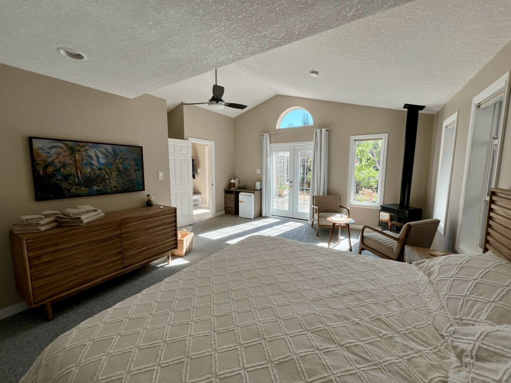 The suite’s open living area with a wall-mounted television, a long dresser and an arched window to the garden.