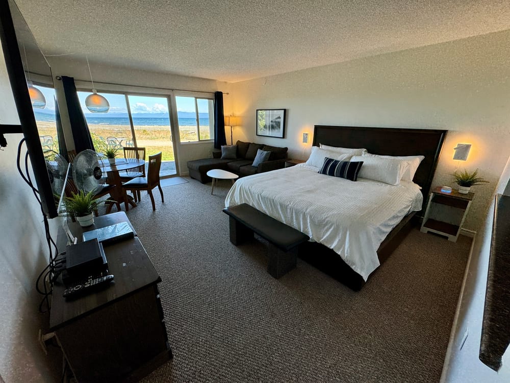 A king bed made up with white linens, facing the window and the water beyond.