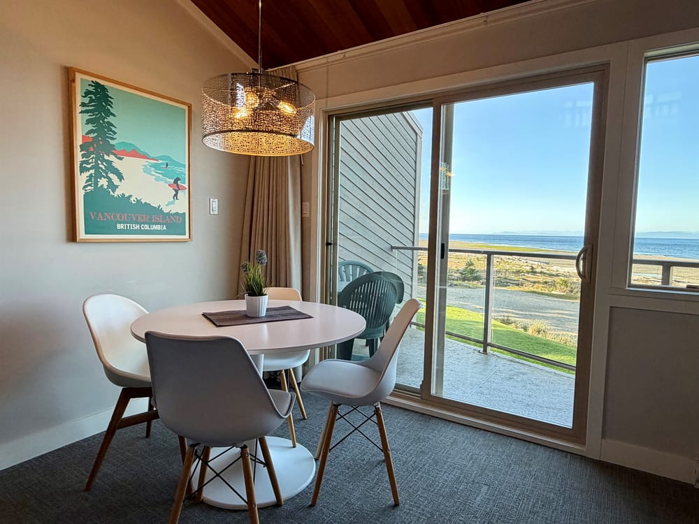 A dining table set beside the window, looking out over the water.